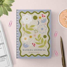 Floral panel diary with a gold pen and cup of hot chocolate on a pink background